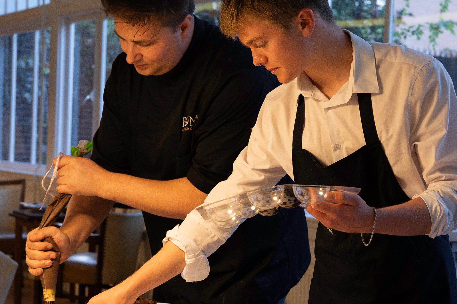 Twee koks van KOM Catering dresseren de desserts op locatie